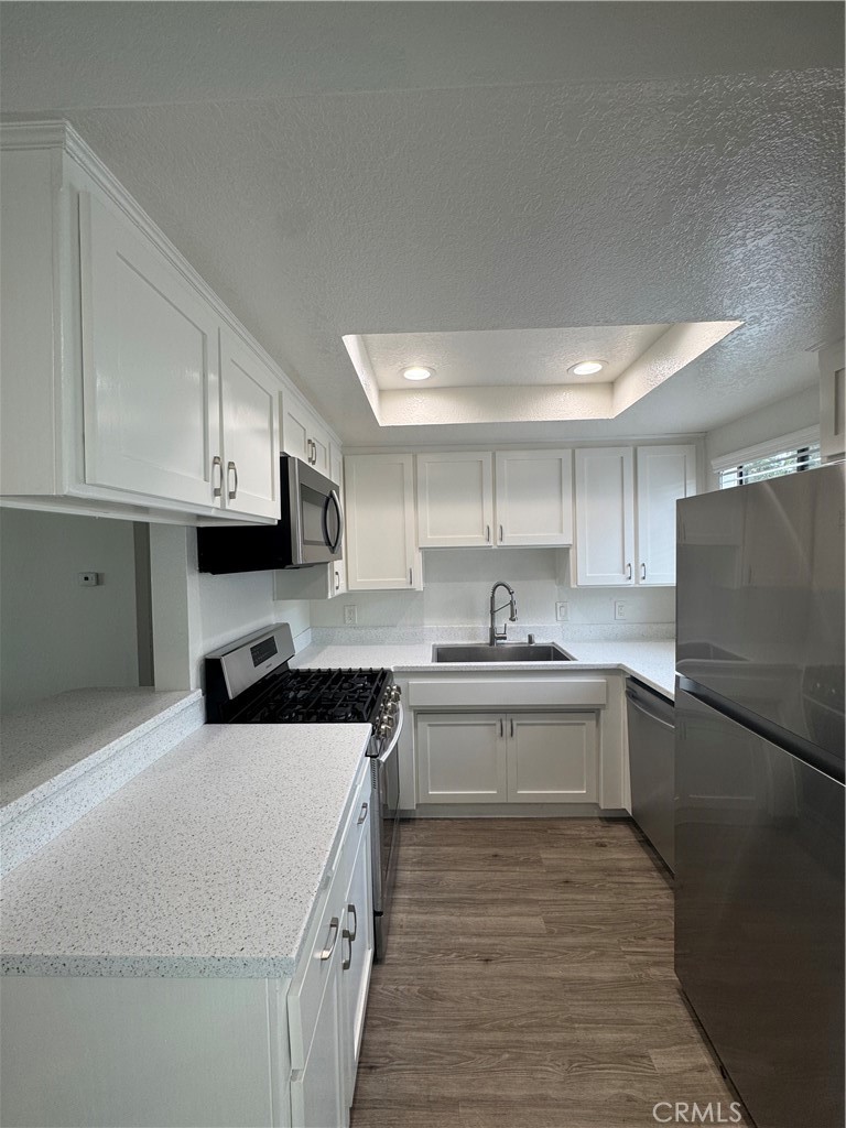 216 Sheldon Street, Unit 1 El Segundo, CA 90245 - Photo 2 of 16 a kitchen with stainless steel appliances granite countertop a stove top oven a sink a refrigerator white cabinets and wooden floor