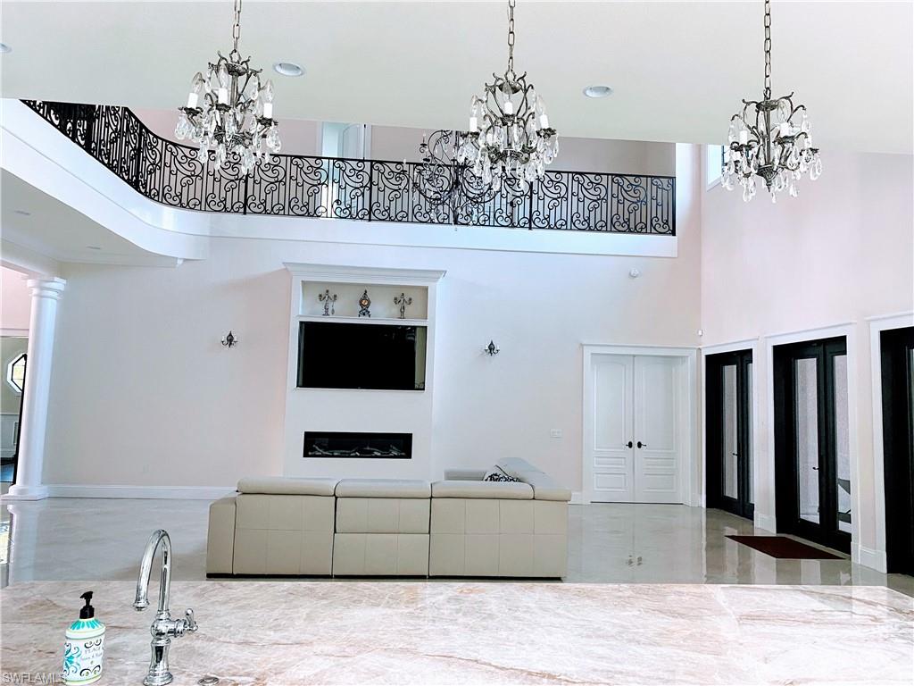 Undisclosed Address Naples, FL 34109 - Photo 11 of 33 a living room with a chandelier and fireplace