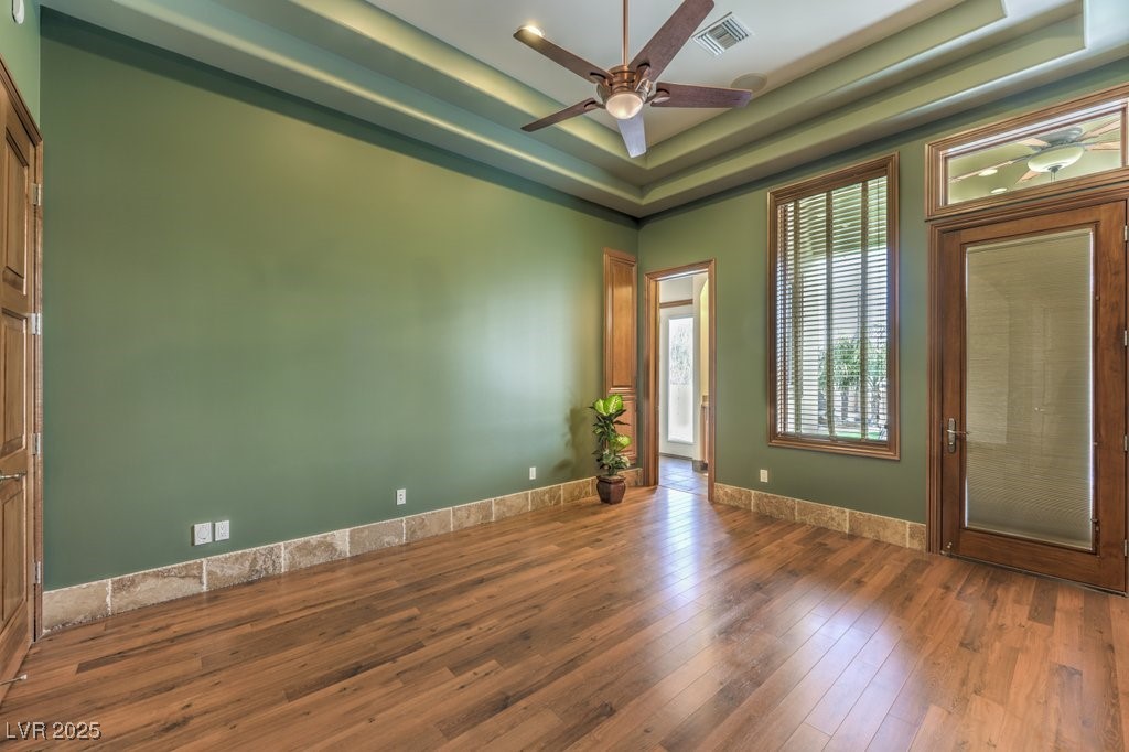 2780 El Camino Road Las Vegas, NV 89146 - Photo 59 of 90 Spare room featuring visible vents, wood finished floors, baseboards, ceiling fan, and a raised ceiling
