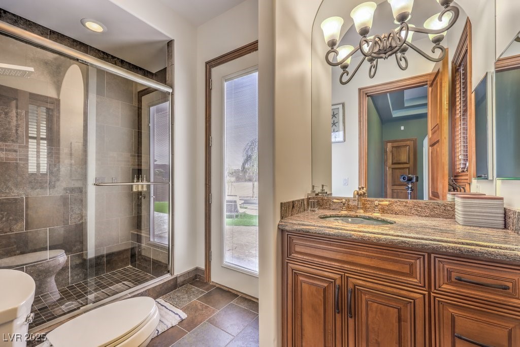 2780 El Camino Road Las Vegas, NV 89146 - Photo 61 of 90 Bathroom with vanity, stone tile floors, toilet, a chandelier, and a stall shower