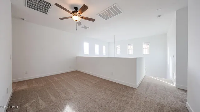 an empty room with chandelier fan and windows