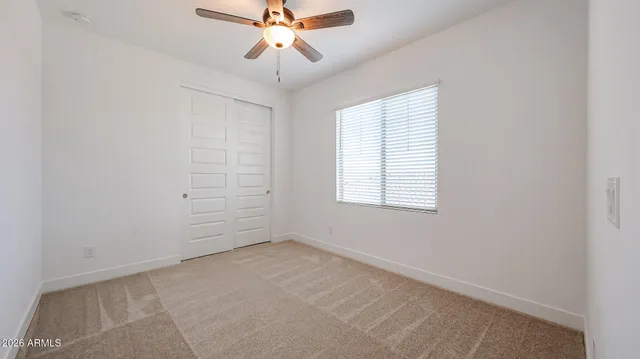 an empty room with windows and fan