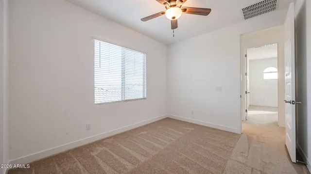 an empty room with a chandelier fan and windows