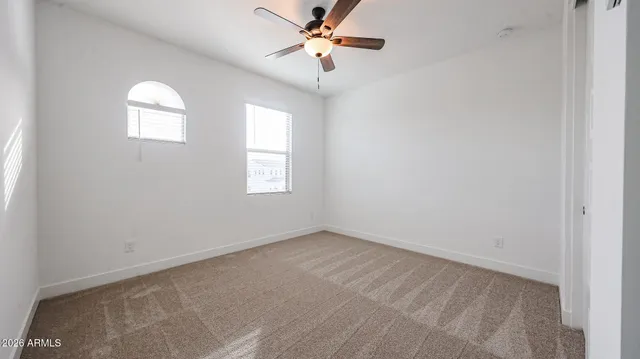 an empty room with windows and fan chandelier fan