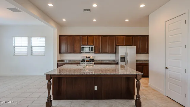 a kitchen with kitchen island a sink a stove a refrigerator and cabinets