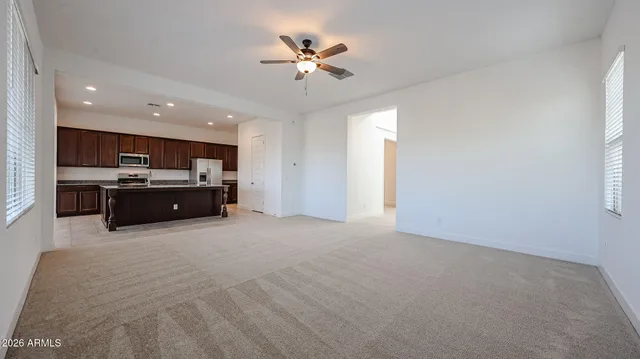 a living room with stainless steel appliances kitchen island furniture and a ceiling fan