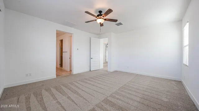 a view of an empty room with a ceiling fan and window