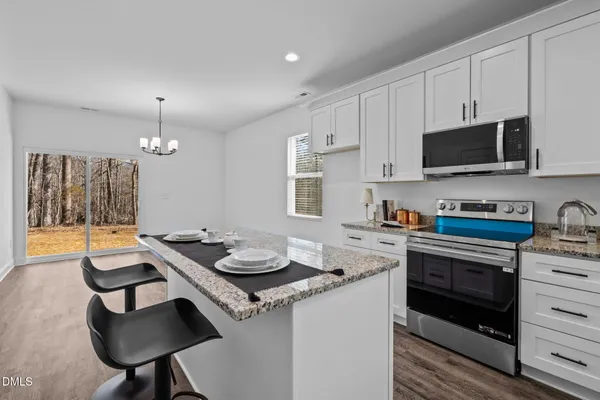 a kitchen with a sink a stove cabinets and wooden floor