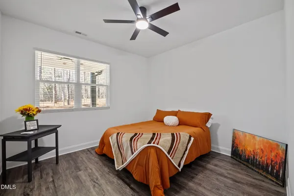 a bed sitting in a bedroom next to a window and a chair