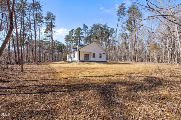 a view of a house with yard and trees in the background