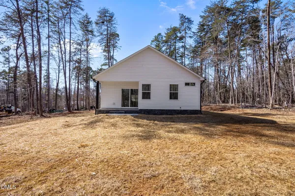 a view of house with yard and trees in the background