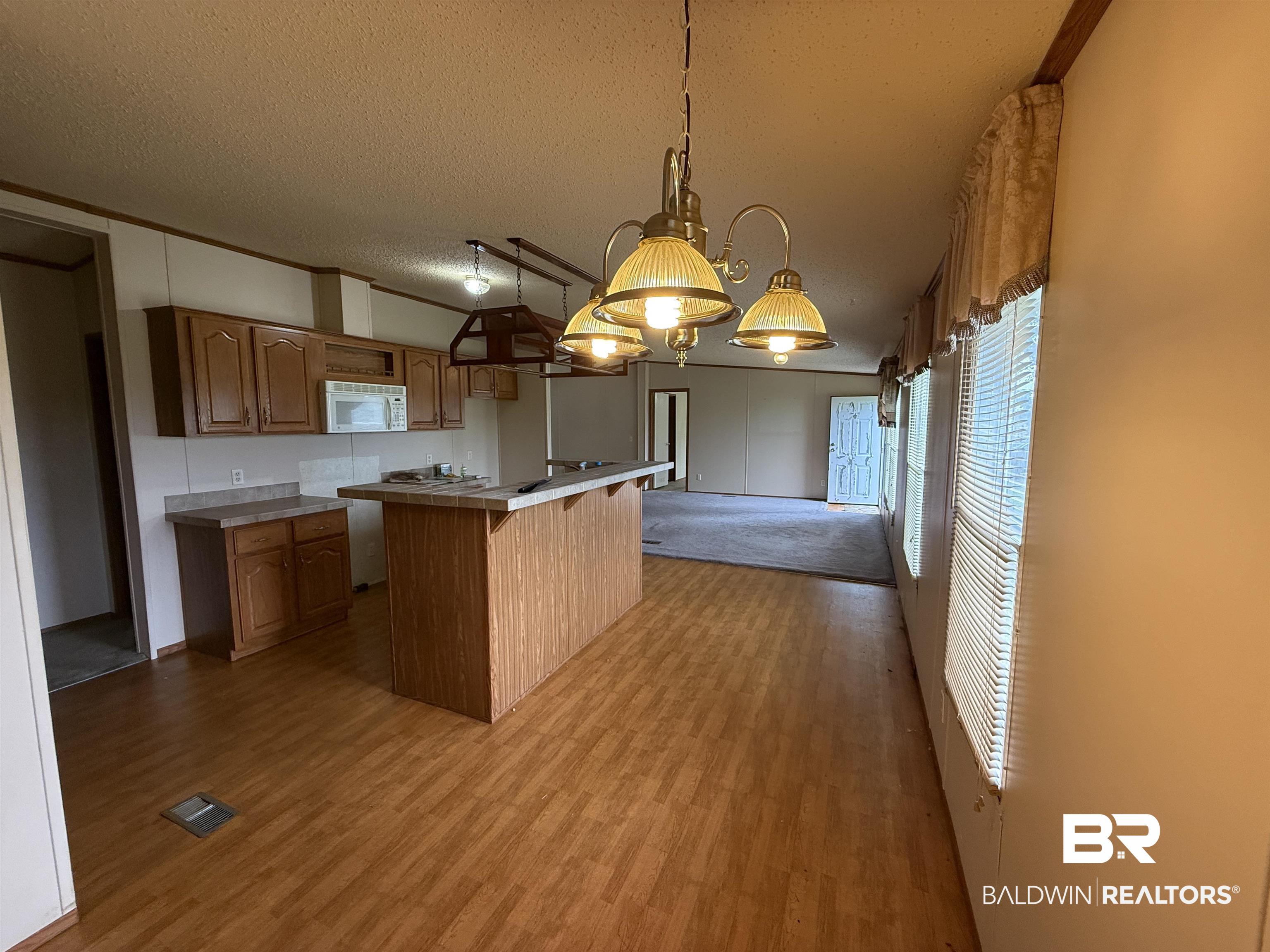 14402 County Road 55 Foley, AL 36535 - Photo 10 of 20 Kitchen featuring light hardwood / wood-style flooring, a textured ceiling, a center island, and pendant lighting