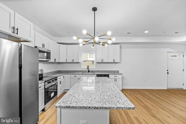 a kitchen with kitchen island granite countertop a sink appliances and cabinets