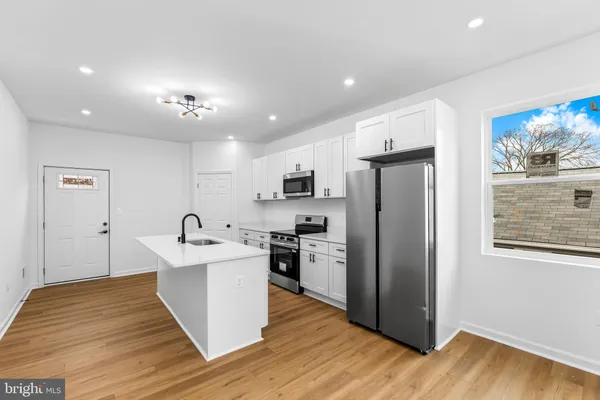 a large kitchen with stainless steel appliances granite countertop a refrigerator and a sink