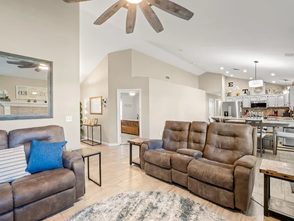a living room with furniture kitchen view and a chandelier