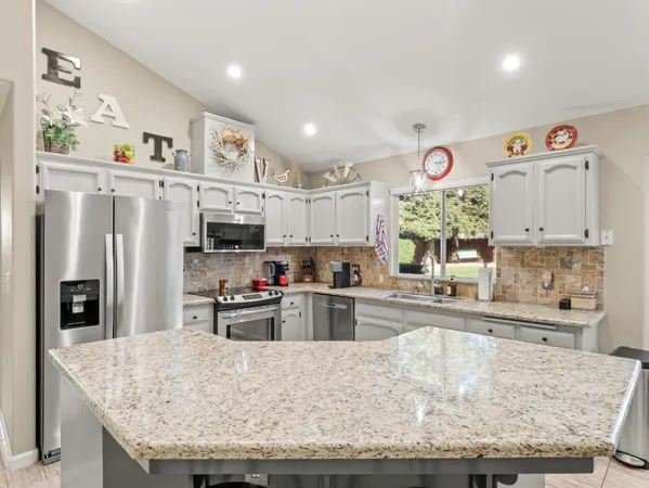 a kitchen with stainless steel appliances granite countertop a sink refrigerator and cabinets