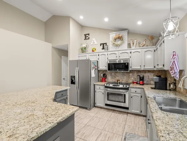 a kitchen with stainless steel appliances granite countertop a sink and a refrigerator