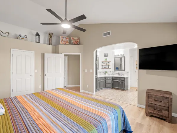 a bedroom with a bed and a flat tv screen on dresser