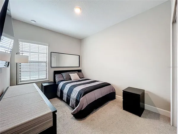 a bedroom with a bed lamp and a large window