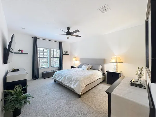 a bedroom with a bed and a potted plant on the dresser