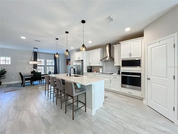 a kitchen with stainless steel appliances a stove a sink a oven a kitchen island with a dining table and chairs