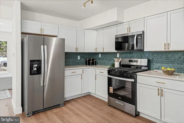 a kitchen with white cabinets stainless steel appliances and a refrigerator
