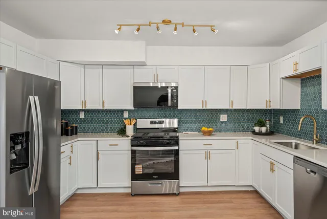 a kitchen with a sink white cabinets and stainless steel appliances