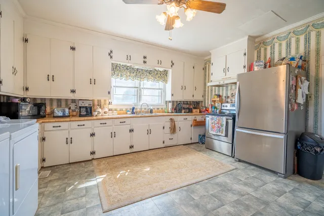 a large white kitchen with granite countertop white cabinets white appliances with a large window