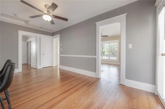 an empty room with wooden floor chandelier fan and windows