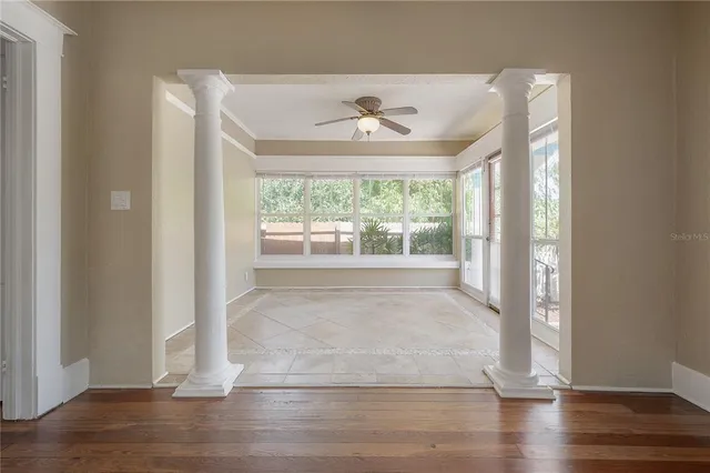 a view of an empty room with wooden floor and a window