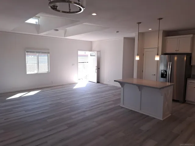 a kitchen with stainless steel appliances granite countertop a refrigerator a sink dishwasher and a oven with wooden floors