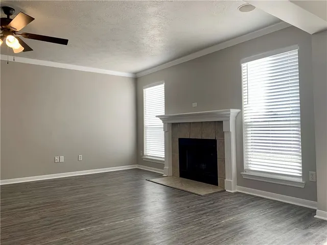 a view of an empty room with wooden floor fireplace and a window