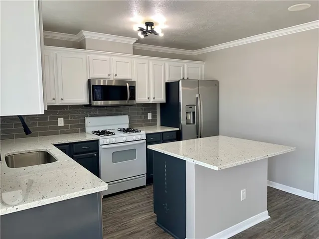 a kitchen with stainless steel appliances granite countertop a white stove top oven a refrigerator a sink and dishwasher