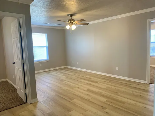 an empty room with wooden floor and fan