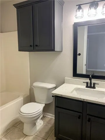 a bathroom with a granite countertop toilet sink and mirror