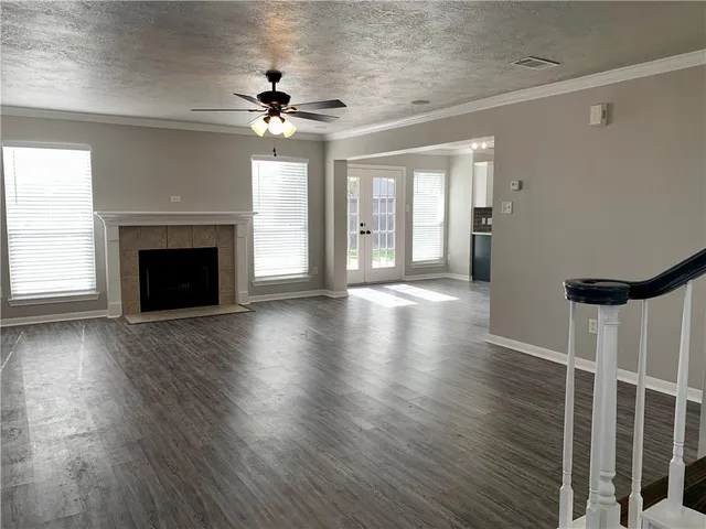 a view of an empty room with wooden floor fireplace and a window
