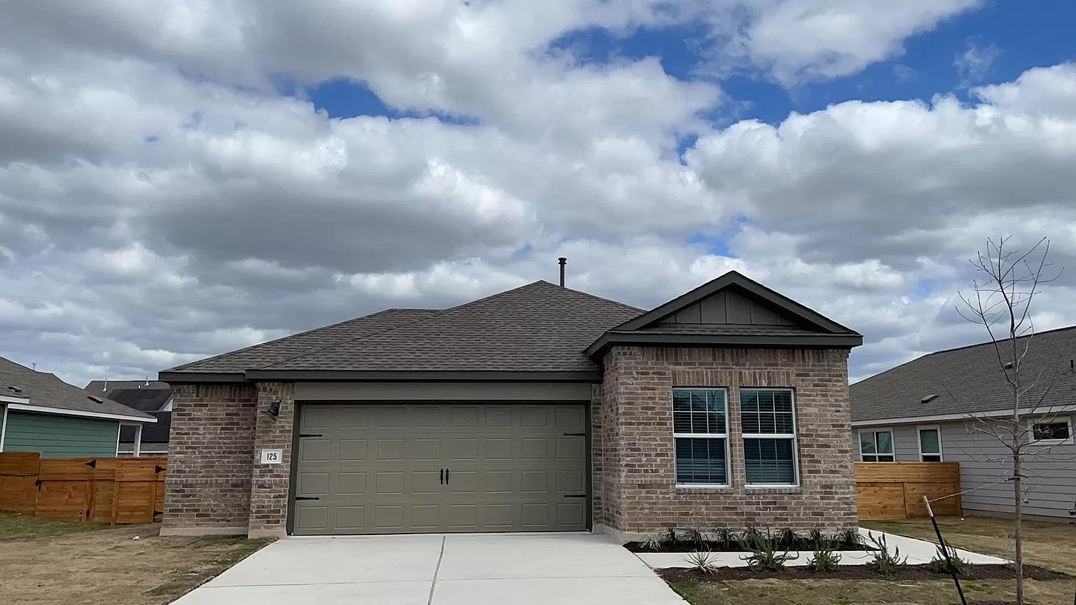 Single story home featuring brick siding, a shingled roof, an attached garage, and driveway