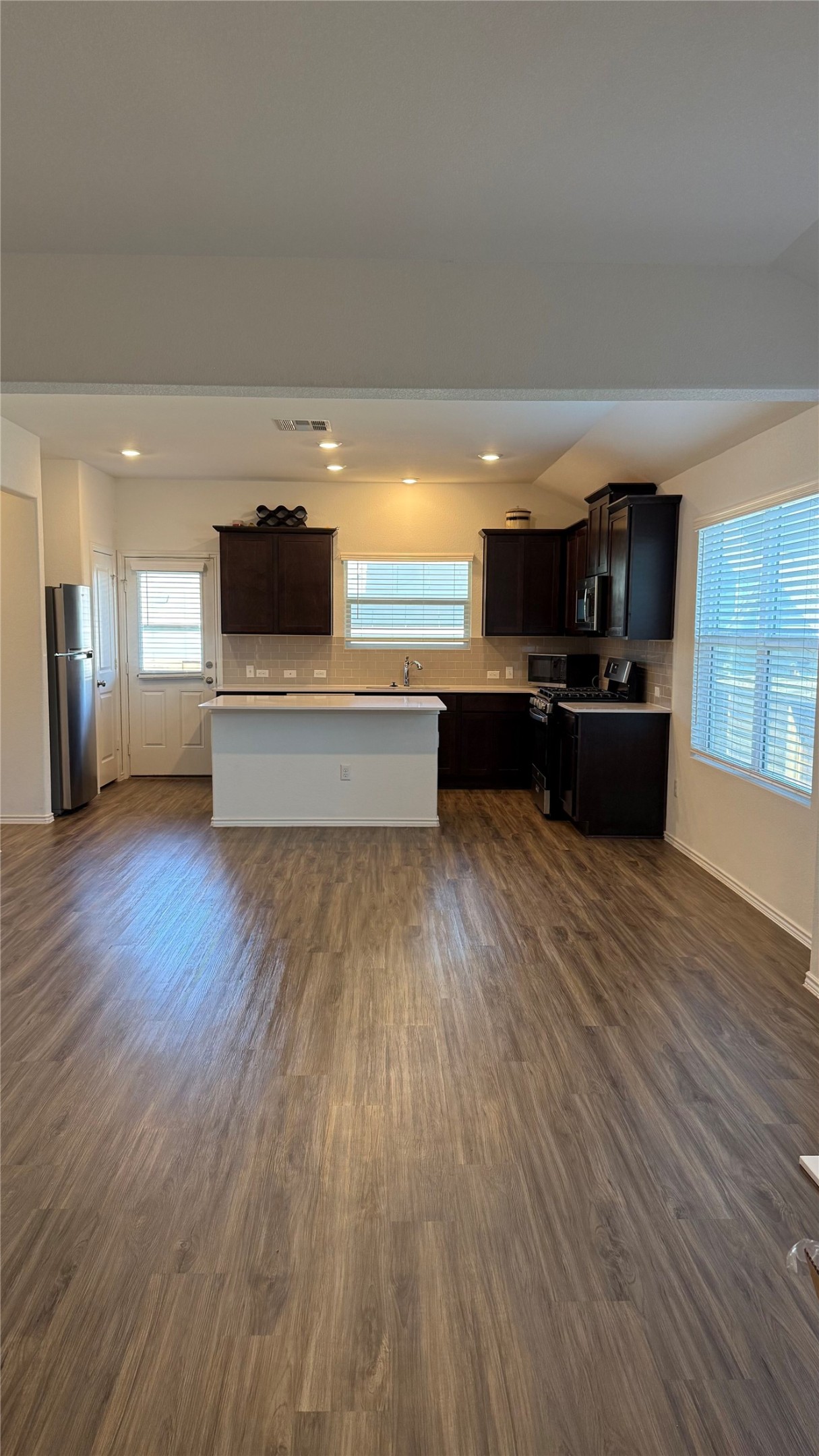 125 Madrid Kyle, TX 78640 - Photo 5 of 23 Kitchen featuring light countertops, dark wood finish cabinets, black range, a center island, and recessed lighting