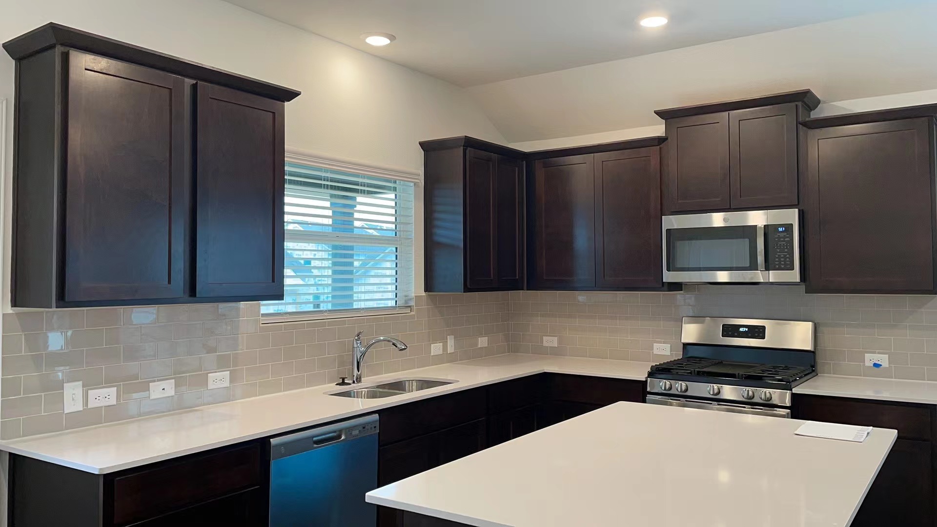 125 Madrid Kyle, TX 78640 - Photo 7 of 23 Kitchen featuring dark wood finish cabinetry, stainless steel appliances, backsplash, a kitchen island, and lofted ceiling