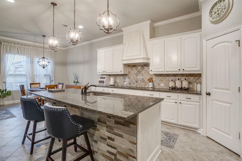 329 Madison Street Burleson, TX 76028 - Photo 11 of 40 a kitchen with kitchen island granite countertop a sink a center island a counter space and cabinets