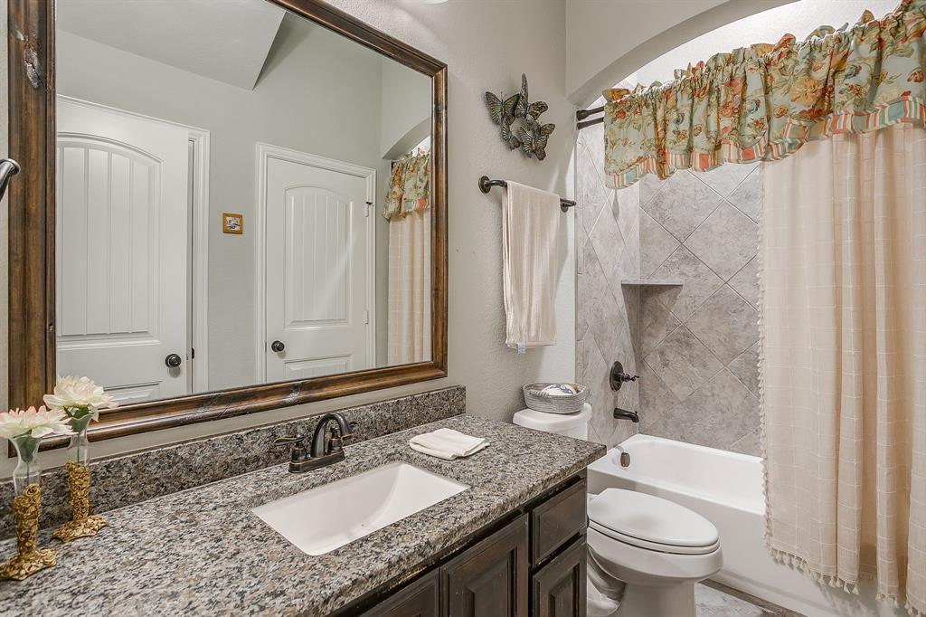 329 Madison Street Burleson, TX 76028 - Photo 29 of 40 a bathroom with a granite countertop sink a mirror a toilet and a bathtub