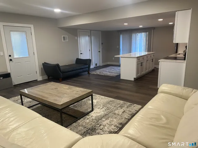 a living room with stainless steel appliances kitchen island granite countertop furniture and a wooden floor