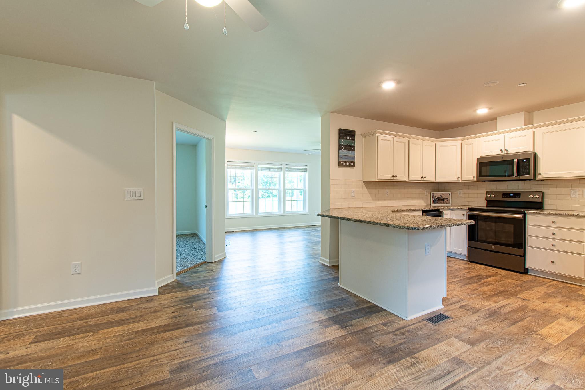 21869 Albie Road Sherwood, MD 21665 - Photo 6 of 38 a kitchen with granite countertop a stove top oven a sink and dishwasher with wooden floor
