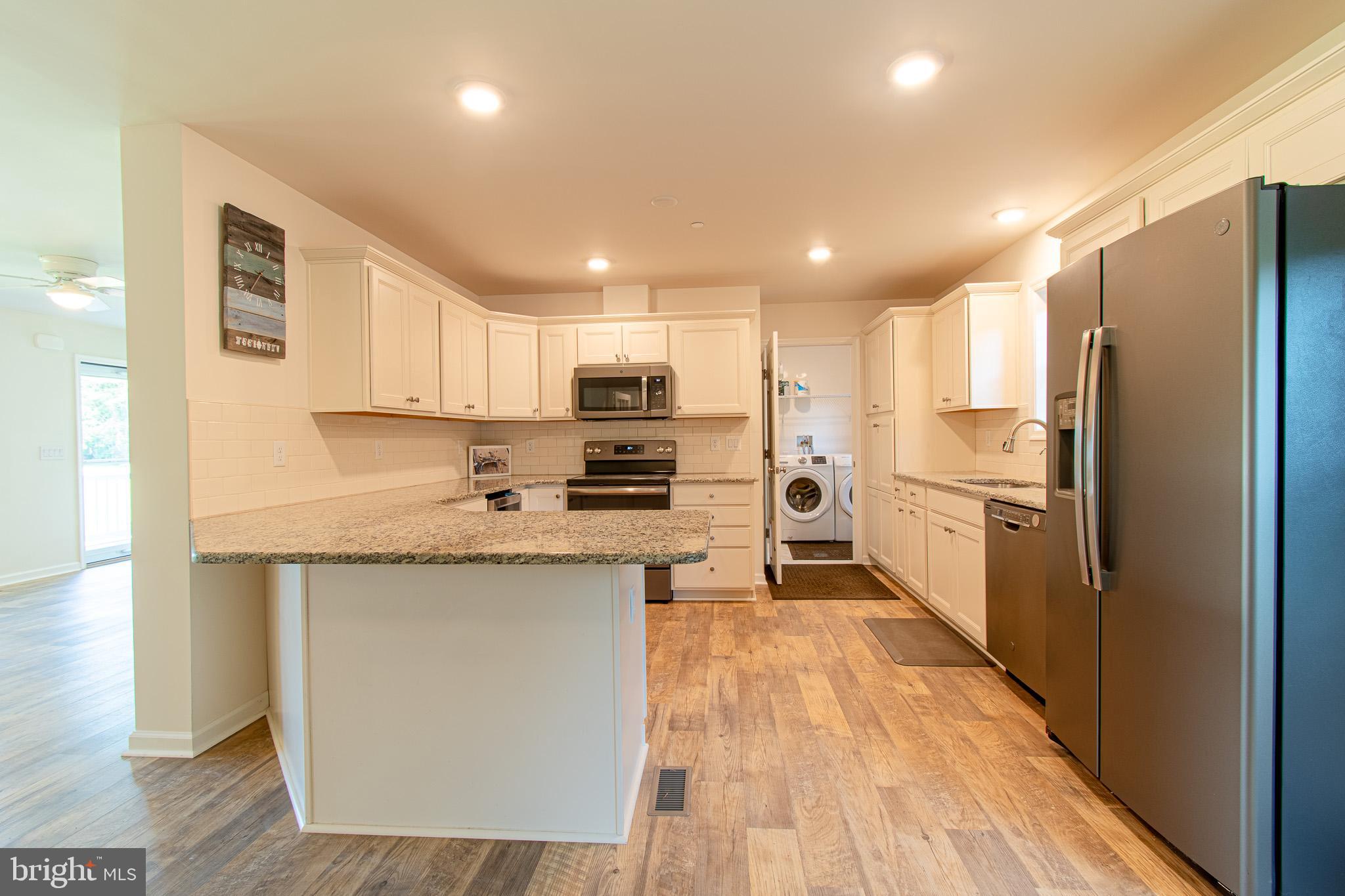 21869 Albie Road Sherwood, MD 21665 - Photo 8 of 38 a kitchen with stainless steel appliances granite countertop a refrigerator a sink dishwasher a stove top oven a kitchen island and chairs with wooden floor