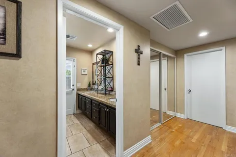 a view of a hallway with wooden floor and a bathroom