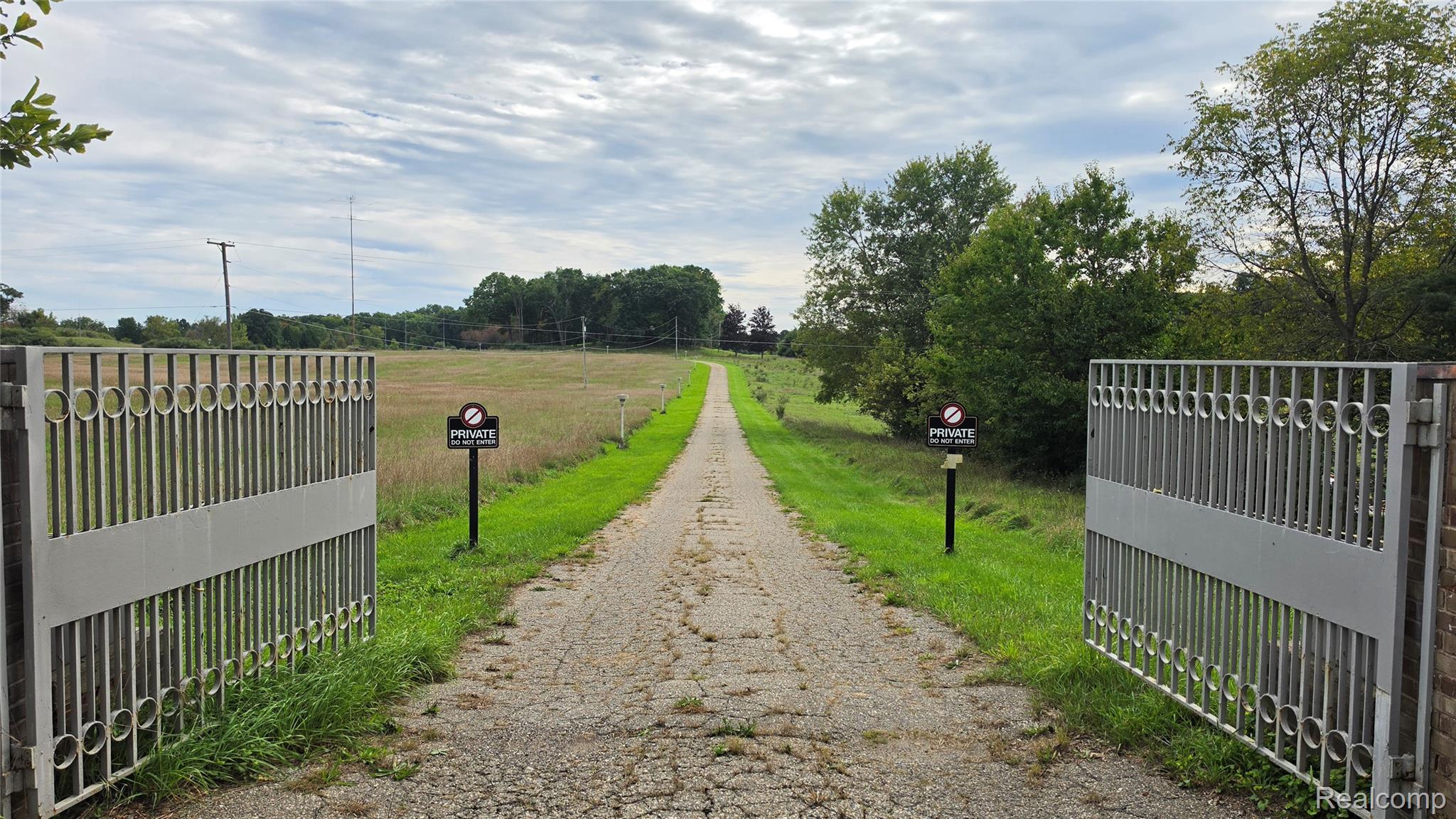2551 Patterson Lk Road Pinckney, MI 48169 - Photo 37 of 37 Open metal gate with brick pillars and a long, paved driveway