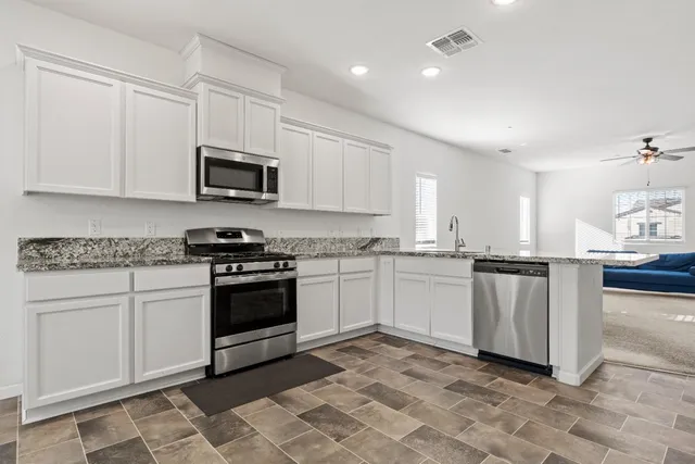 a kitchen with granite countertop white cabinets and stainless steel appliances