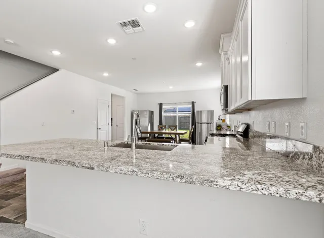 a view of a kitchen with kitchen island a sink stainless steel appliances and living room view