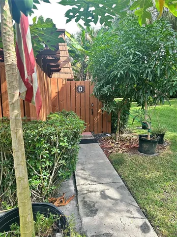a view of a backyard with potted plants and large trees