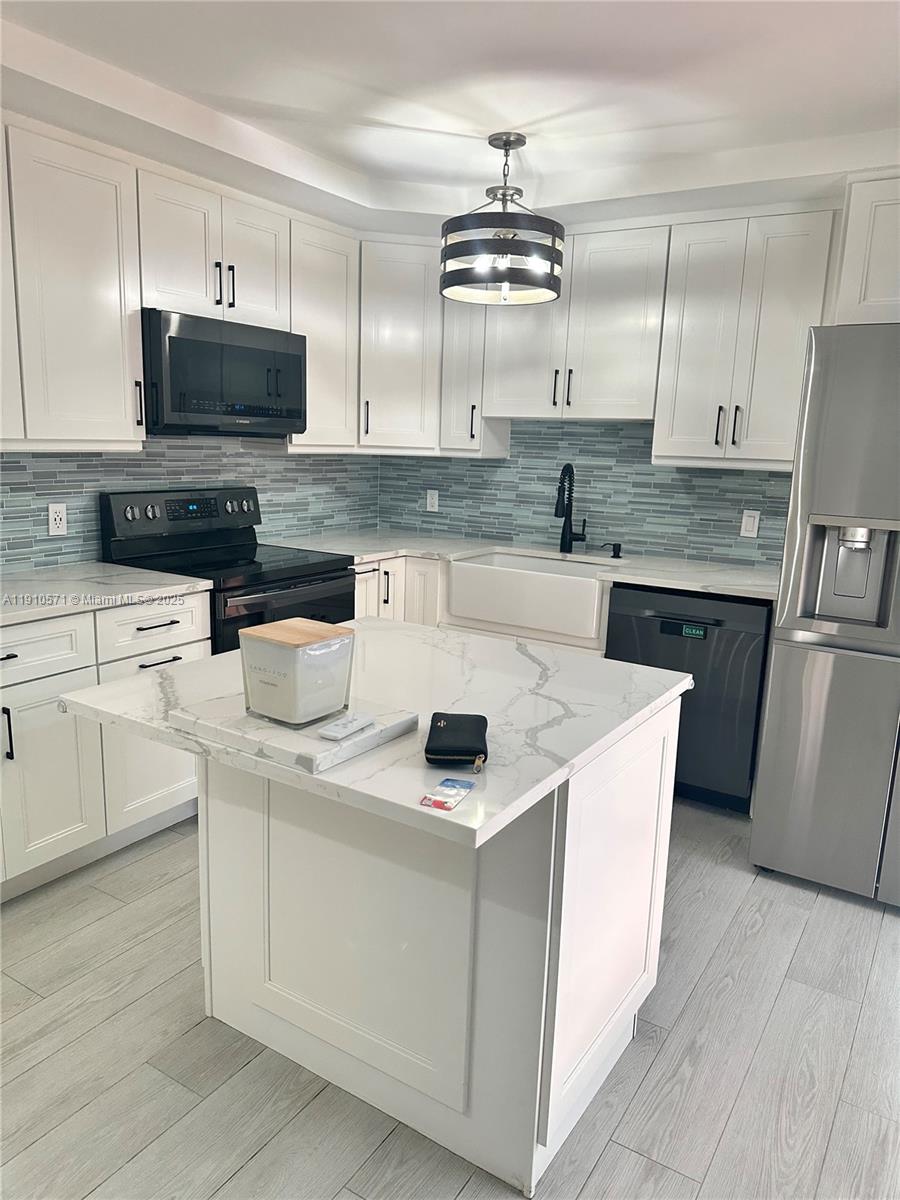 9156 Southwest 23rd Street, Unit D Davie, FL 33324 - Photo 6 of 14 a kitchen with stainless steel appliances a stove a sink a microwave and cabinets